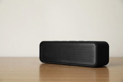 One,Black,Portable,Bluetooth,Speaker,On,Wooden,Table.,Audio,Equipment