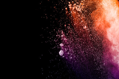 Orange purple powder explosion on black background. Orange purple color dust splash.
