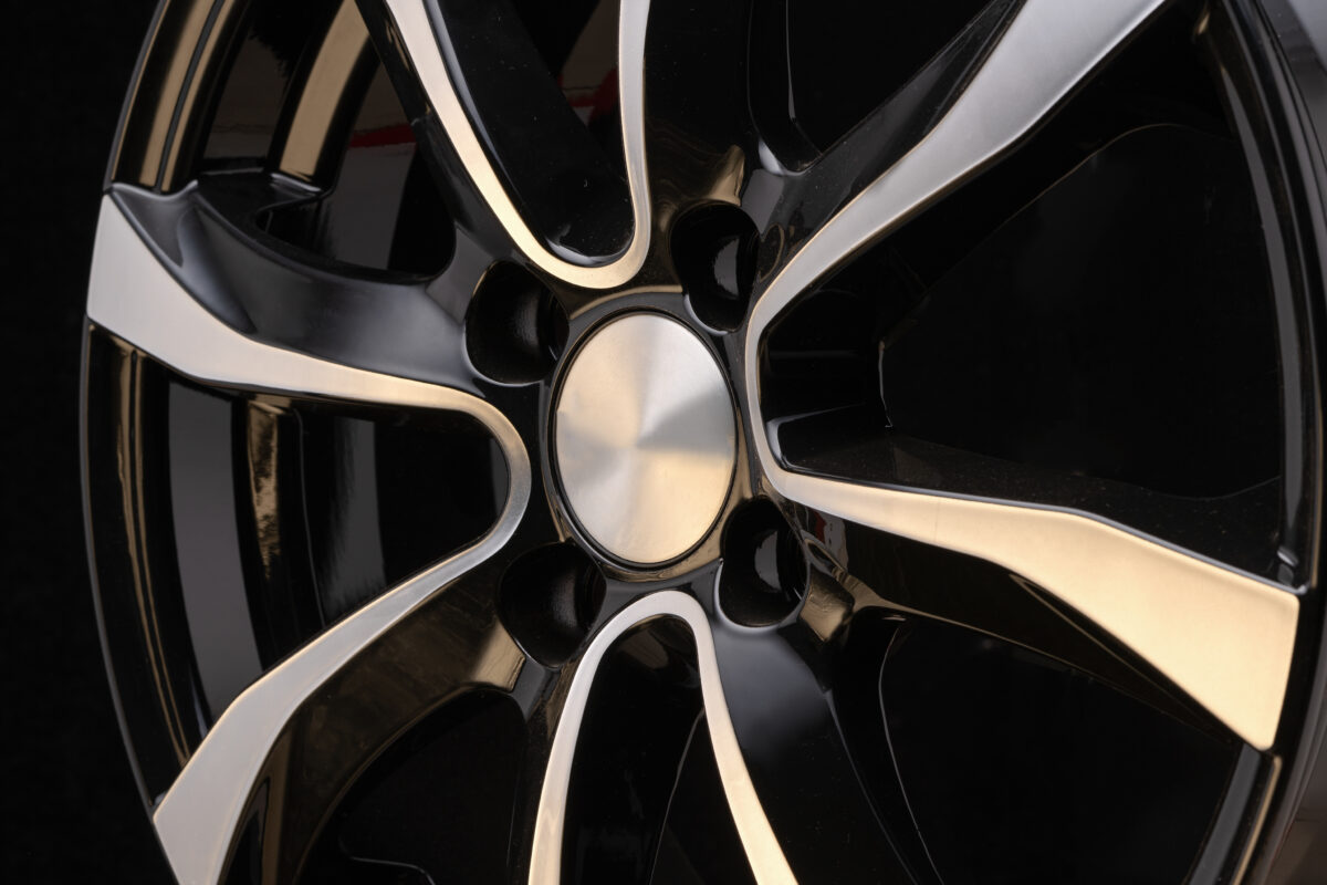 car alloy wheel close-up of the disc element, curves smooth lines of the wheel spokes, polished front surface. black background, concept