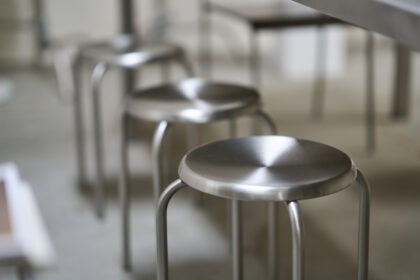 Row of metal stools under a table in a modern interior design setting