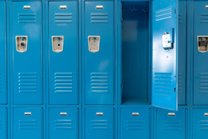 Single open empty blue metal locker along a nondescript hallway in a typical US High School.  No identifiable information included and nobody in the hall.