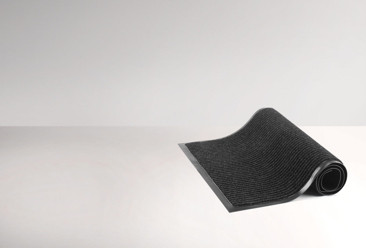Rolled black protective door mat on a white background