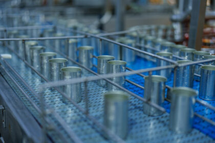 Cans are lined up on conveyor belt in fish processing industry, showcasing efficiency and precision of modern manufacturing. scene reflects dedication to quality and productivity