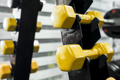 Closeup,Of,Yellow,Plastic,Dumbbells,On,A,Vertical,Dumbbell,Stand.